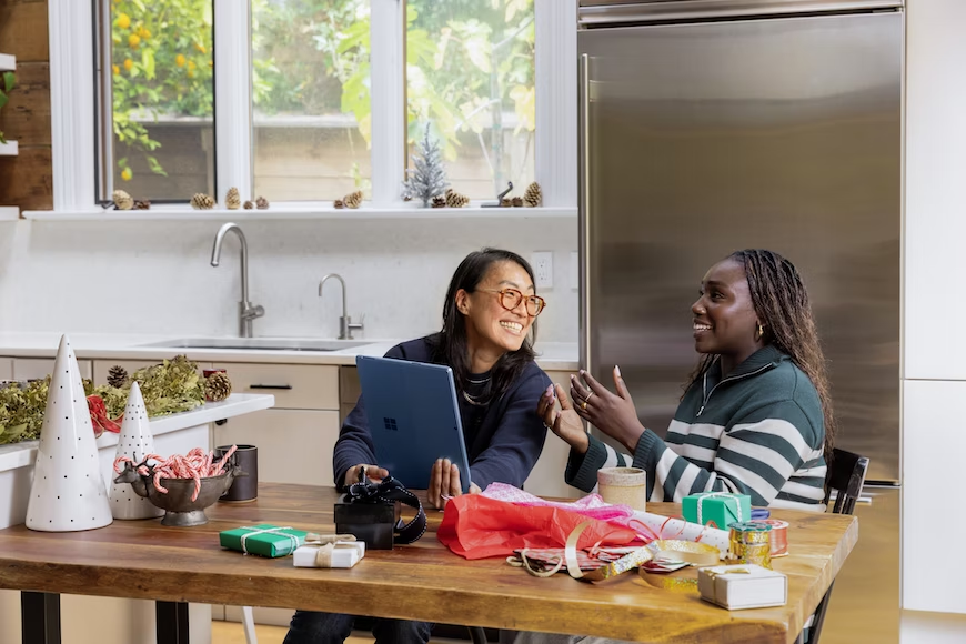 Deux femmes parlant ensemble et regardant une tablette tactile Microsoft bleue devant un frigo 