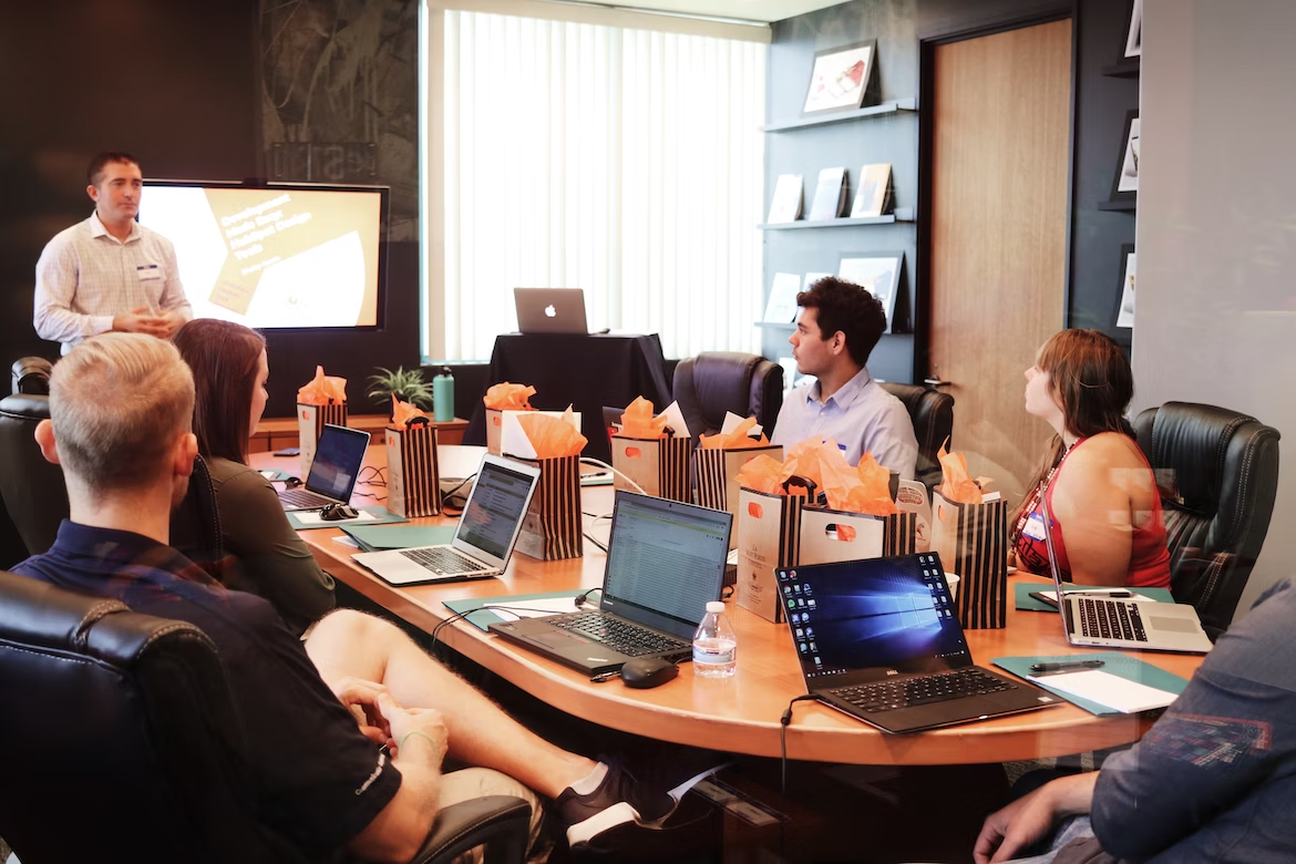 Salariés d'une entreprise en pleine réunion sur une grande table avec des ordinateurs