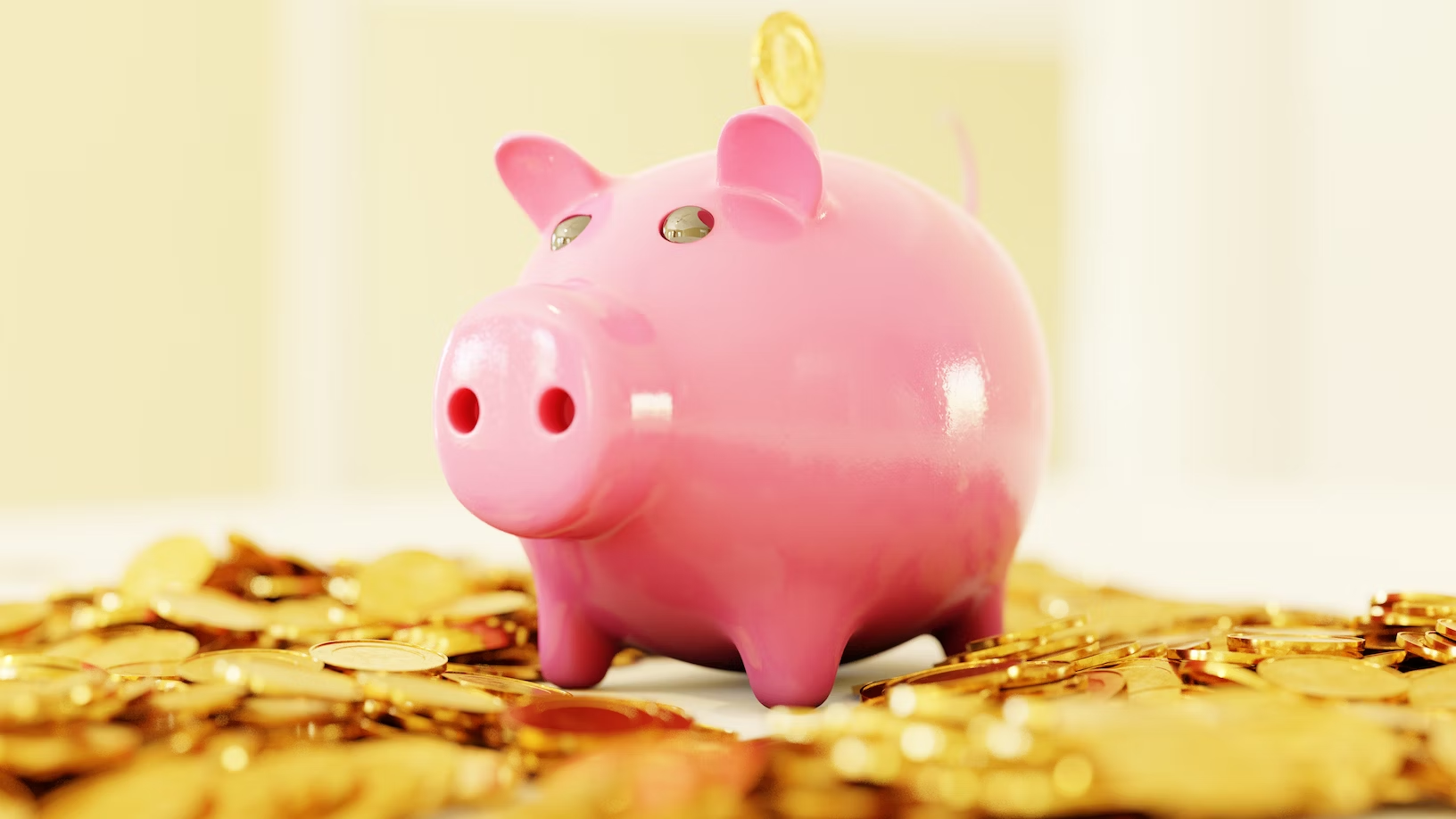 Une tirelire en forme de cochon rose et posée sur une pile de pièces de monnaie