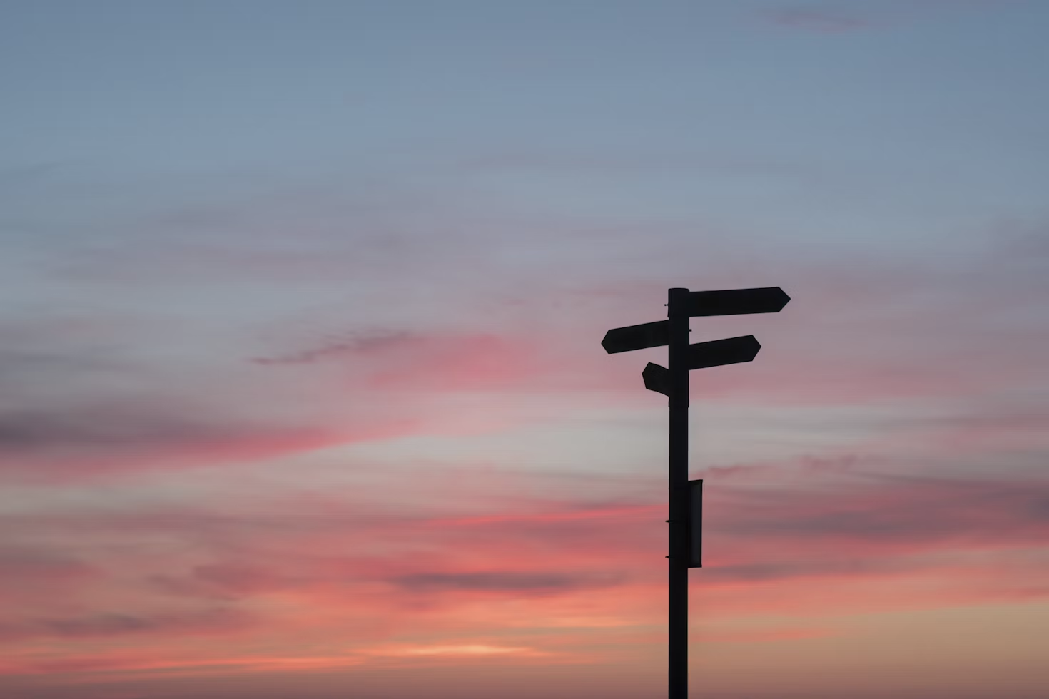 panneau indicateur avec quatre flèches indiquant la droite et la gauche devant un coucher de soleil