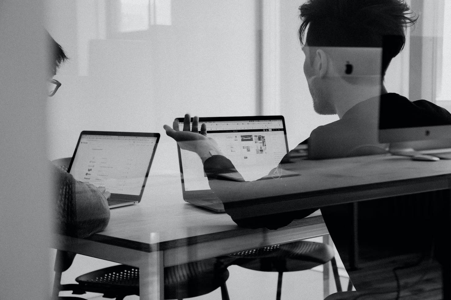 Deux hommes regardant leur ordinateur dans une salle de réunion assis à une table