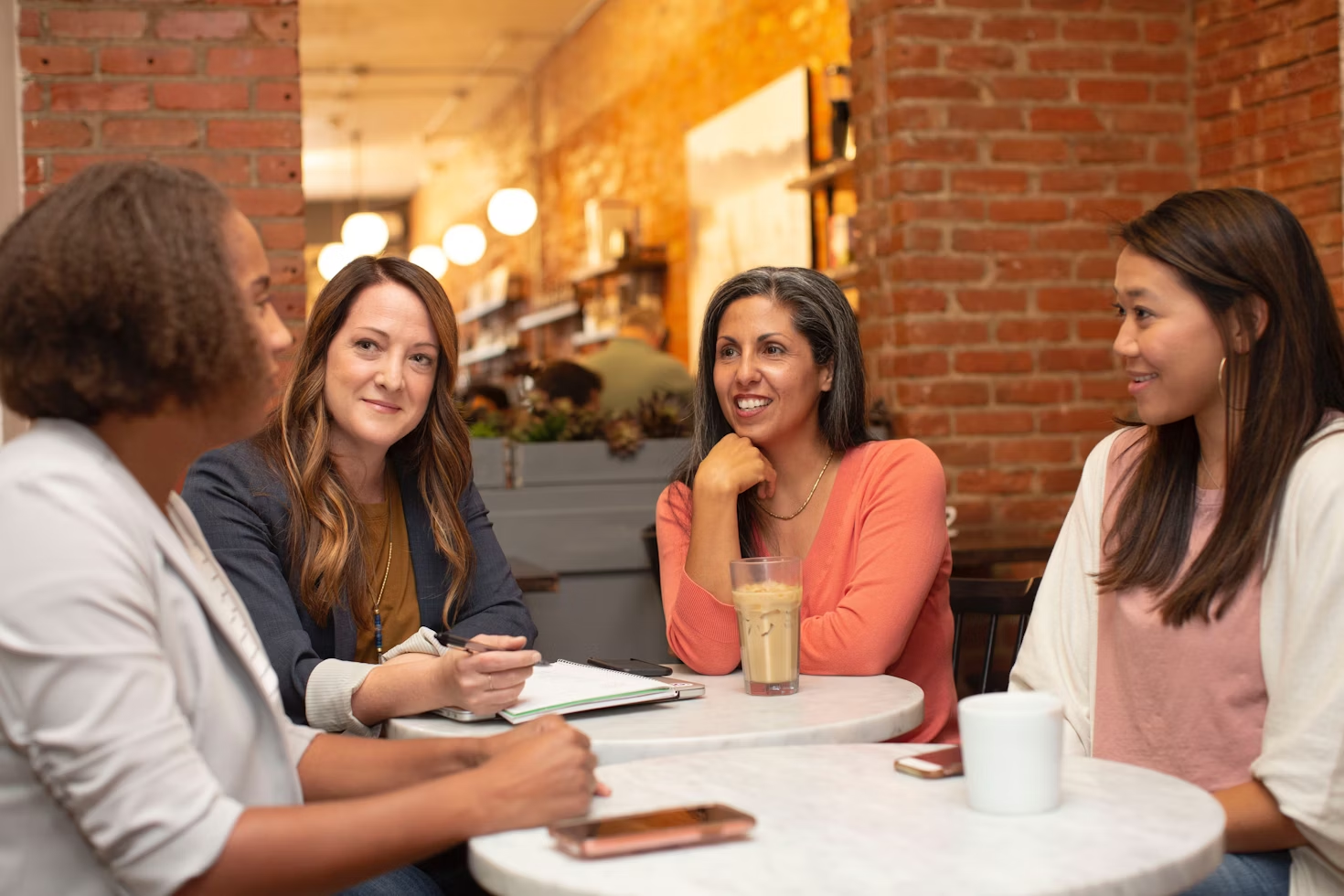 quatre femmes assises autour de cafés et discutant entre elles