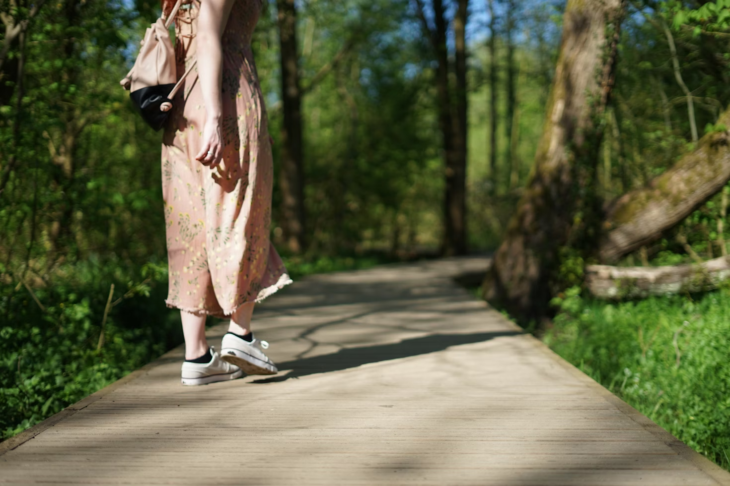 Femme portant une combinaison beige avec des fleurs marchant sur un chemin dans une forêt
