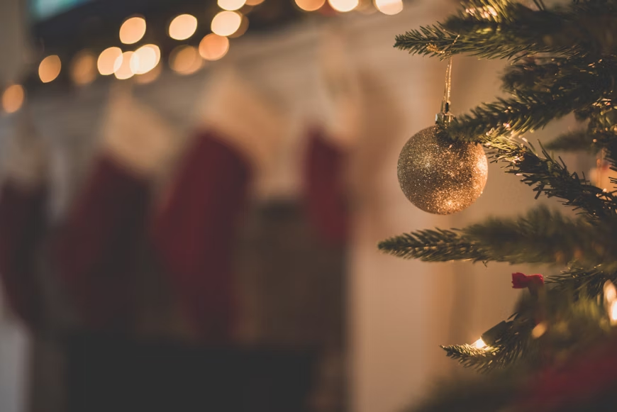 Sapin de Noël avec une boule de Nöel dorée et avec une cheminée surmontée de chaussettes rouges